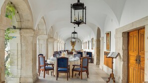 A long corridor with tables and chairs, arched ceilings, and a wooden door on the right. - Pousada Castelo de Palmela - Historic Hotel (Palmela)