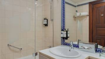 Une salle de bain avec une douche à parois de verre, un lavabo blanc avec un miroir et une porte en bois.