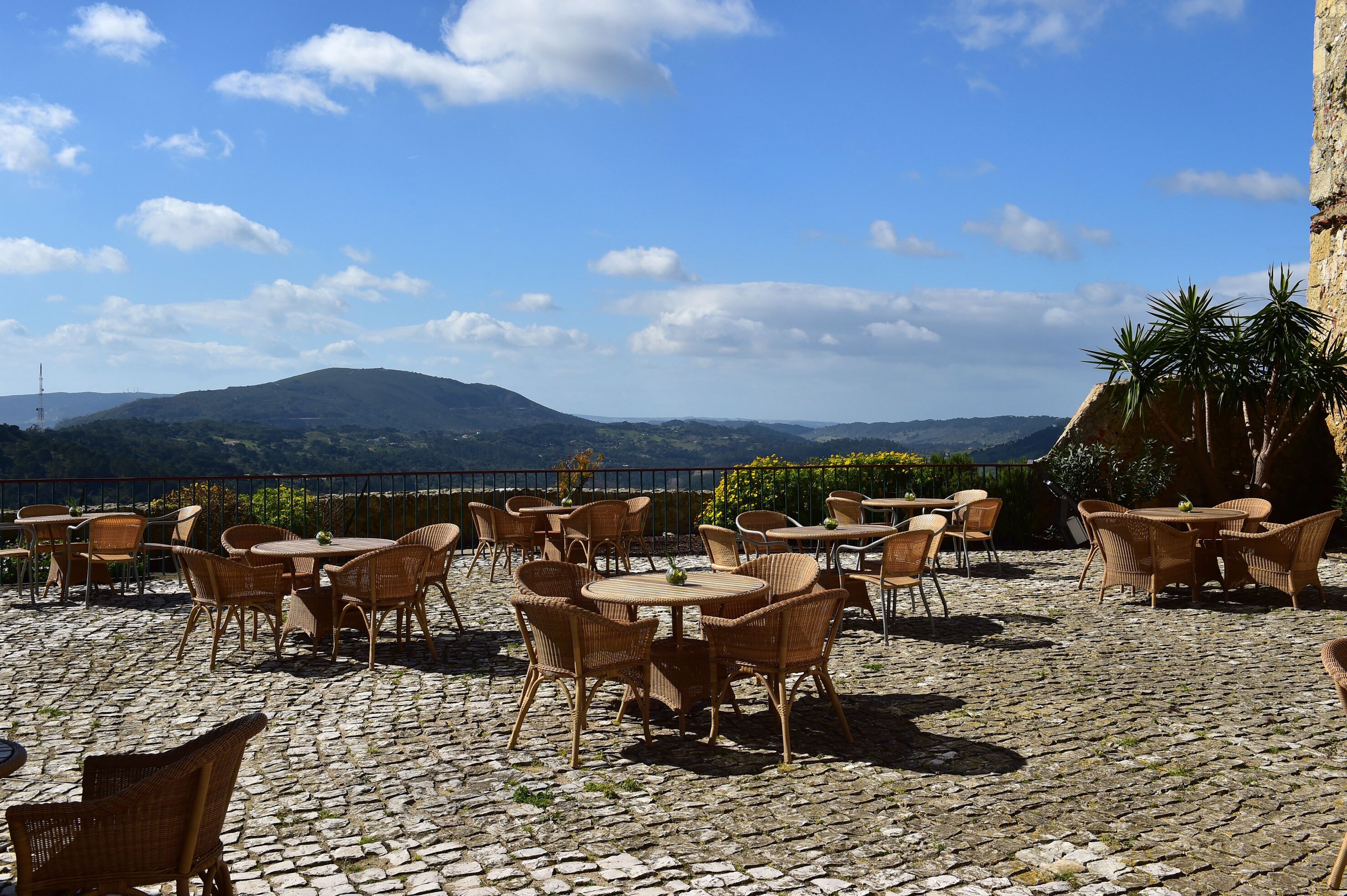 An outdoor café with wicker furniture and a cobblestone floor.