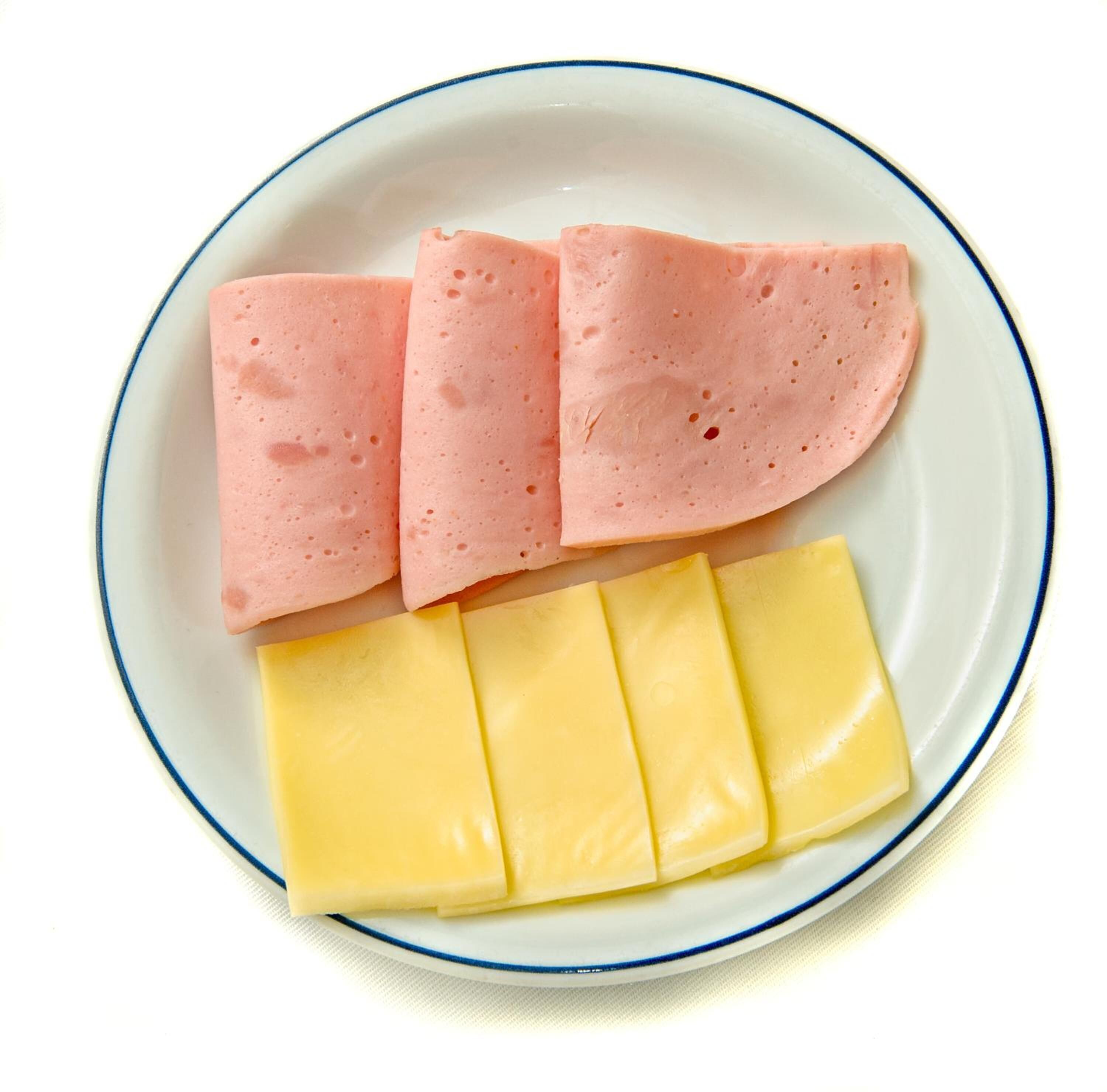 Un plato con lonchas de jamón rosado y queso amarillo.