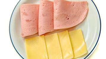 Un plato con lonchas de jamón rosado y queso amarillo.