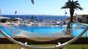 Un espace piscine doté de chaises longues et d’un hamac, avec vue sur la mer.