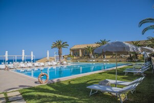 Una piscina al aire libre, sombrillas, sillones reclinables de piscina