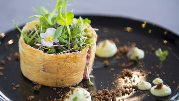 A pastry dish with greens and flowers on a black plate.