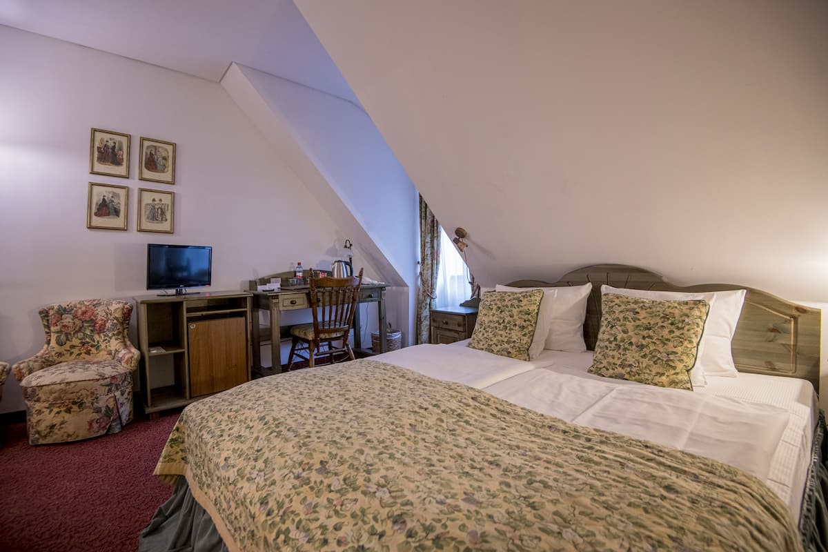 A bedroom with a large bed, a desk, a chair, and a television.