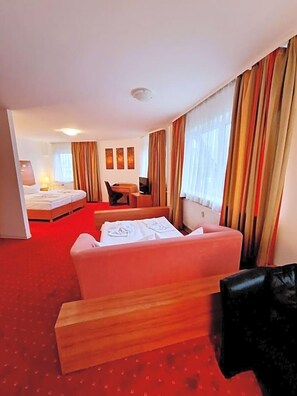 Una habitación de hotel con cama, escritorio, silla y sofá.
