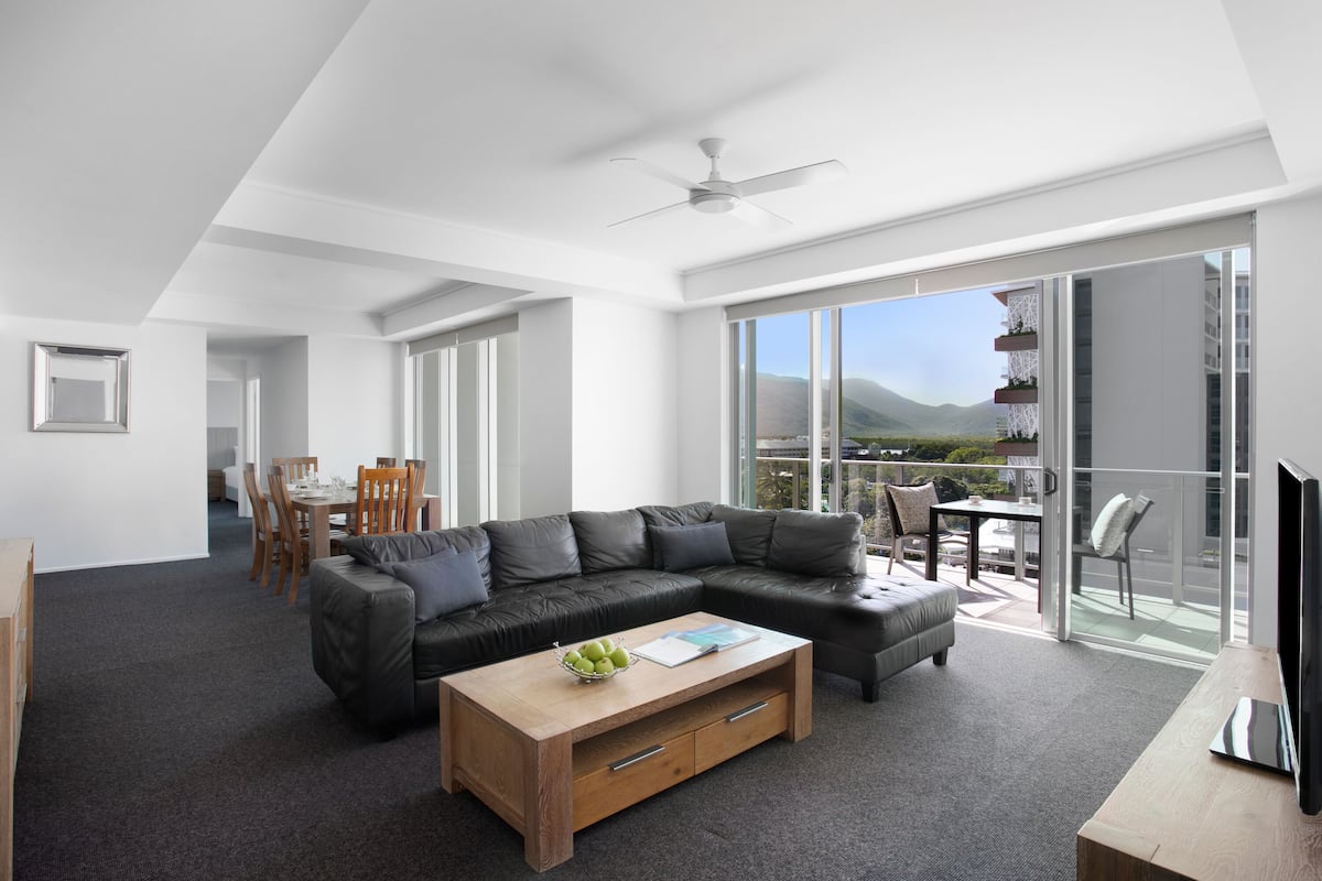 A modern living room with a sectional sofa, a wooden coffee table, and a dining area with chairs.