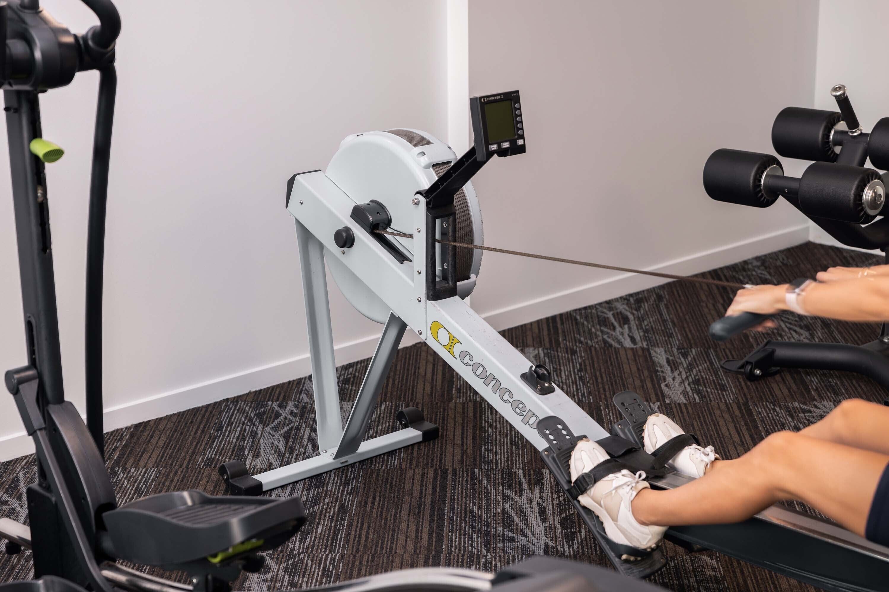 Ein Rudergerät in einem Fitnessstudio mit digitalem Display und Fußstützen.