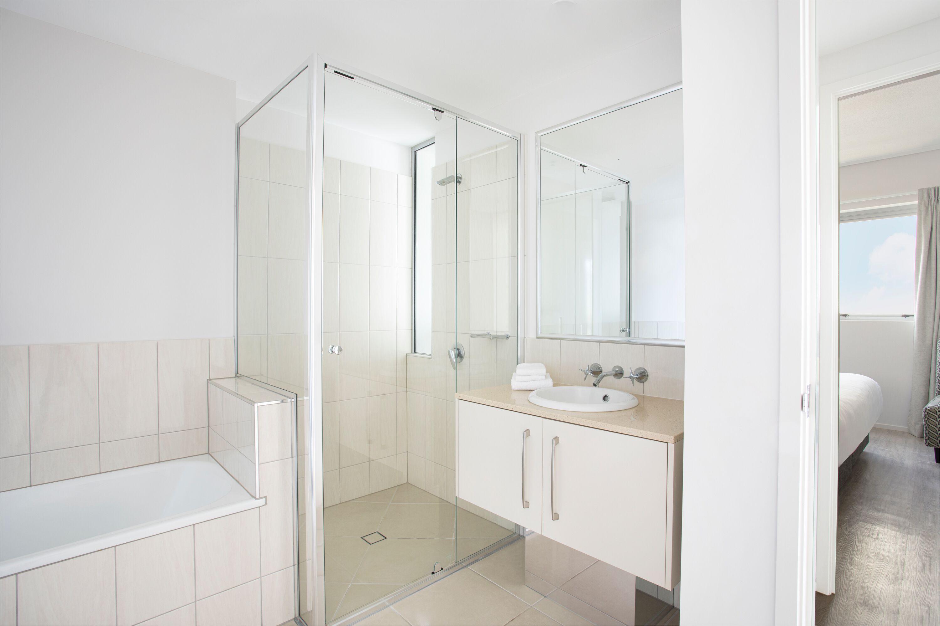 Un baño moderno con ducha acristalada, lavamanos y espejo.
