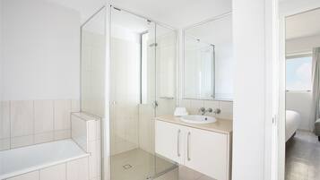 Un baño moderno con ducha acristalada, lavamanos y espejo.
