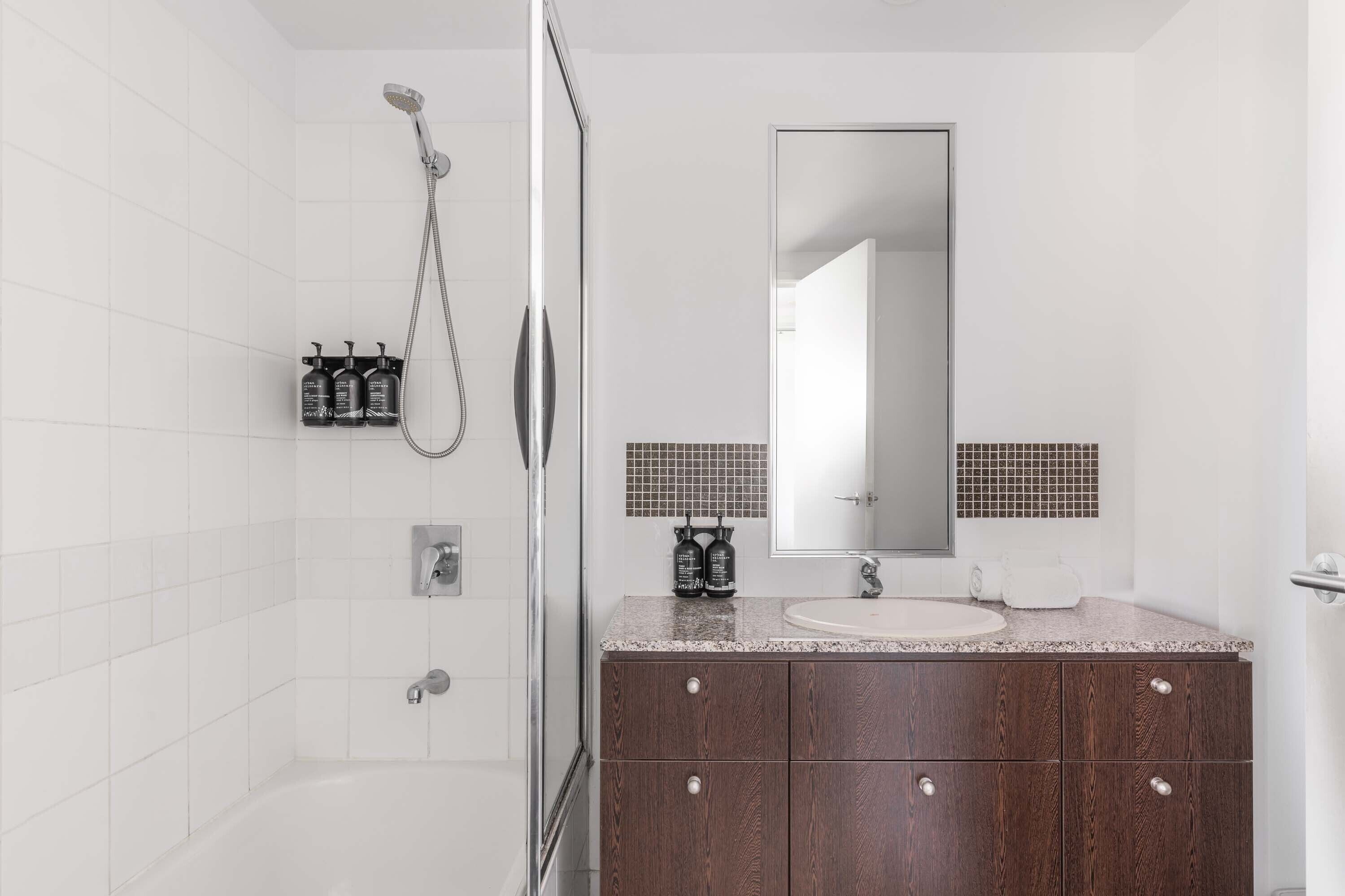 Un bagno moderno con doccia, lavandino e specchio.