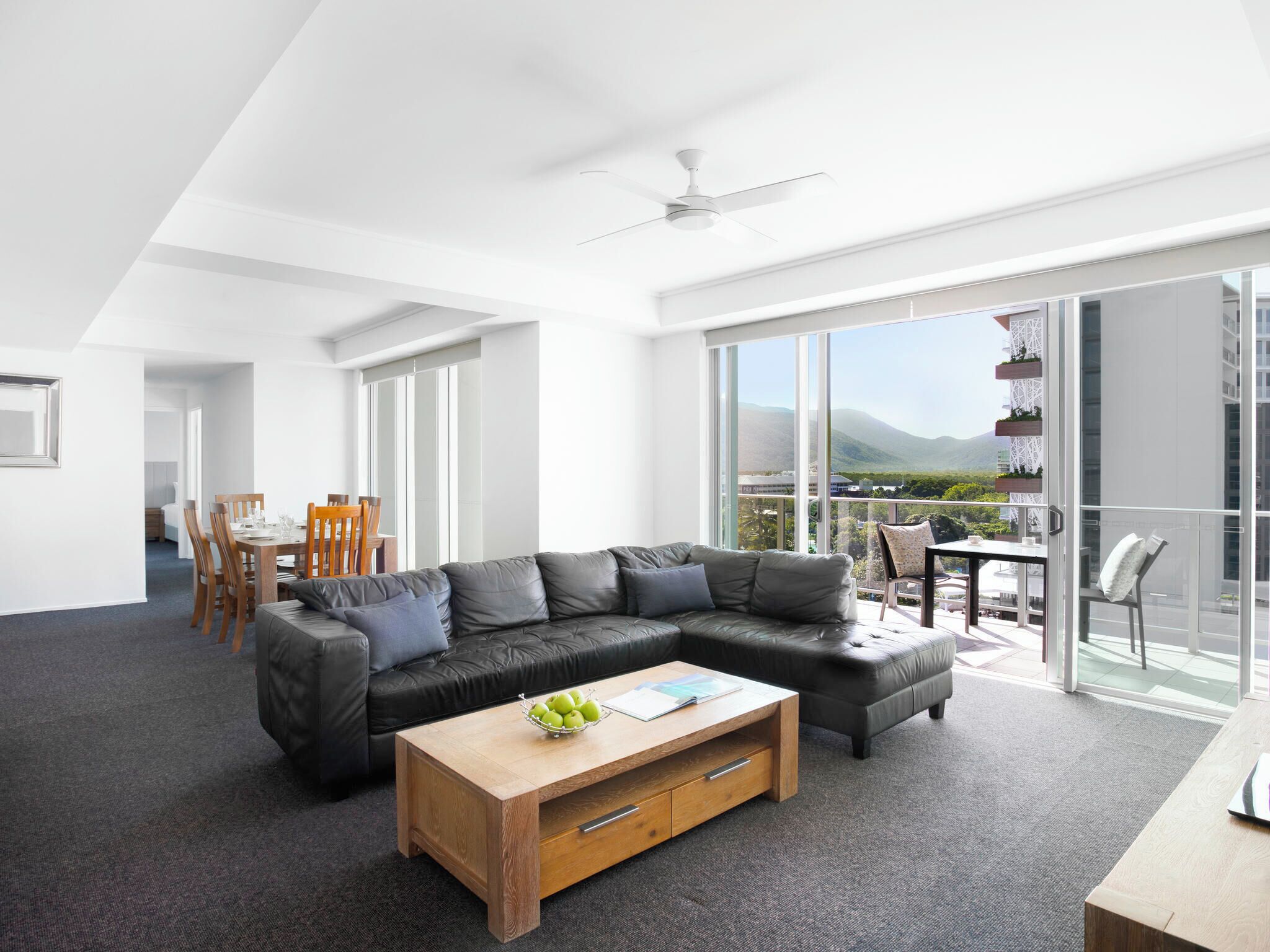 A modern living room with a sectional sofa, a wooden coffee table, and a dining area with a table and chairs.