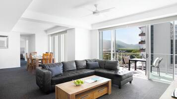 A modern living room with a sectional sofa, a wooden coffee table, and a dining area with a table and chairs.