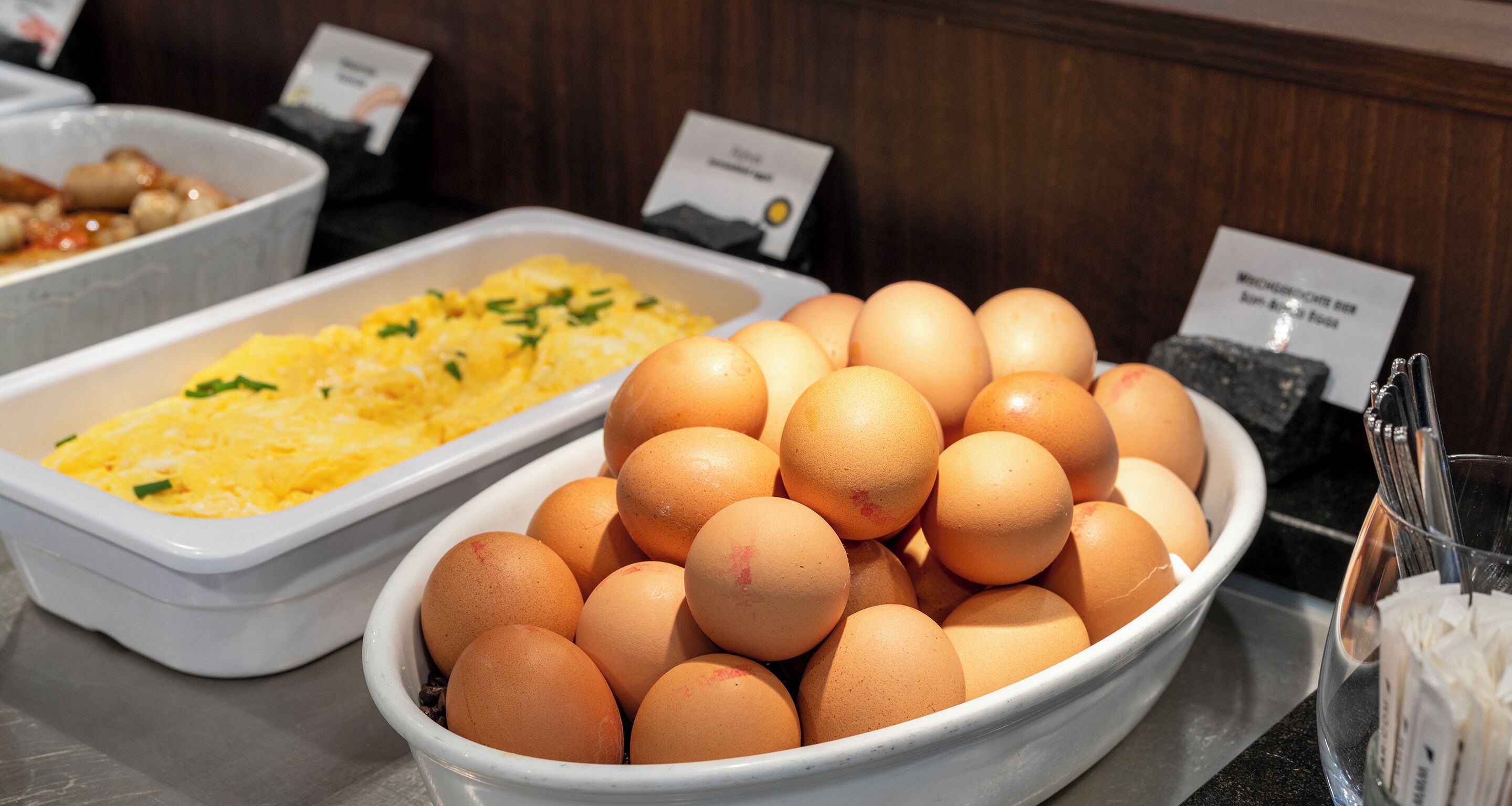 A buffet with a bowl of eggs and a dish of scrambled eggs.