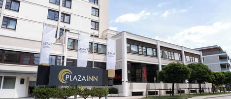 A multi-story hotel with a sign reading 'Plaza Inn.'