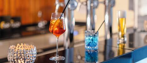 Un bar con una copa de bebida de color ámbar, un vaso decorativo azul y un candelabro.