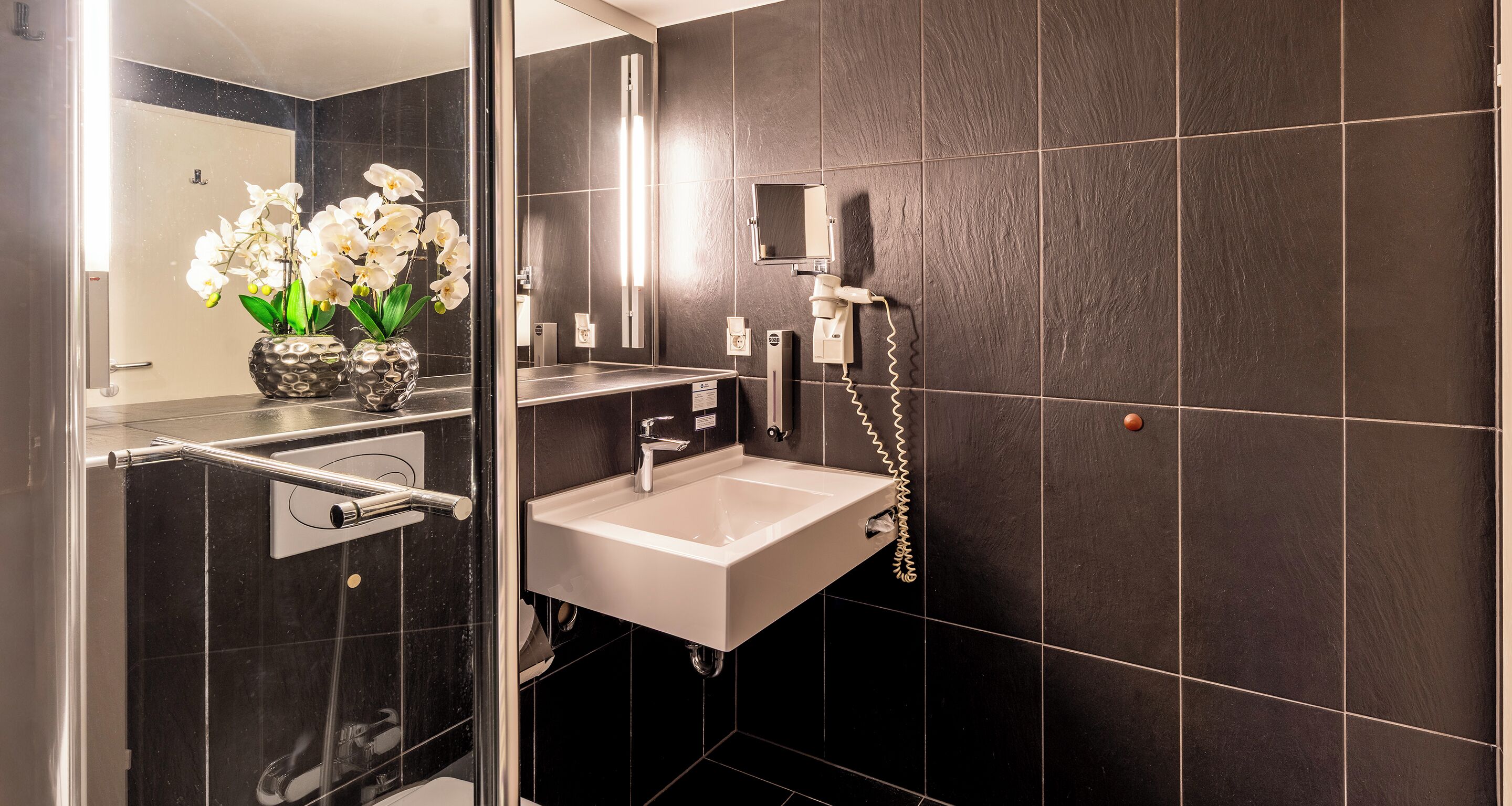 Un baño moderno con cabina de ducha de vidrio, un lavabo blanco y un espejo.