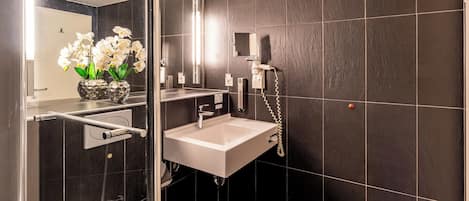 Un baño moderno con cabina de ducha de vidrio, un lavabo blanco y un espejo.