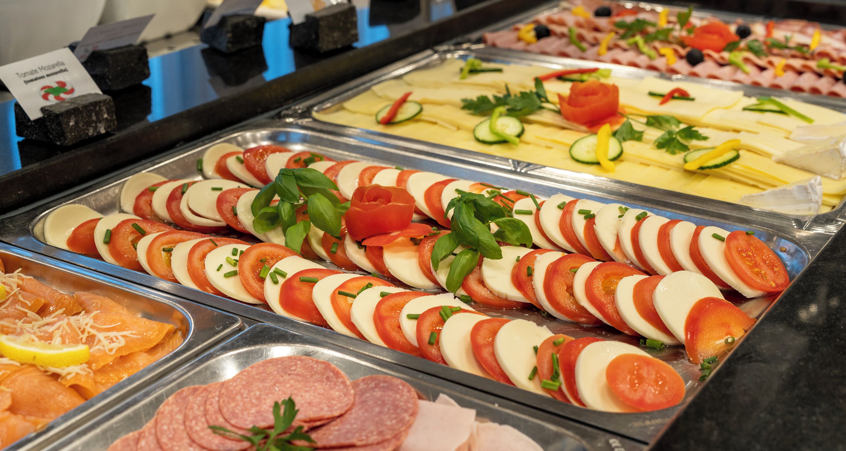 Un buffet proposant une variété de plats, notamment des tomates en tranches, du fromage et de la charcuterie.