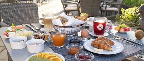 Una mesa de desayuno con cruasanes, fruta y bebidas.