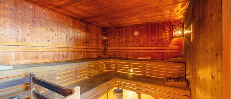 Una sauna con bancos de madera y una cuenca de piedra.