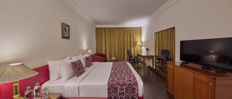 Una habitación de hotel con cama, escritorio, televisor y una silla.