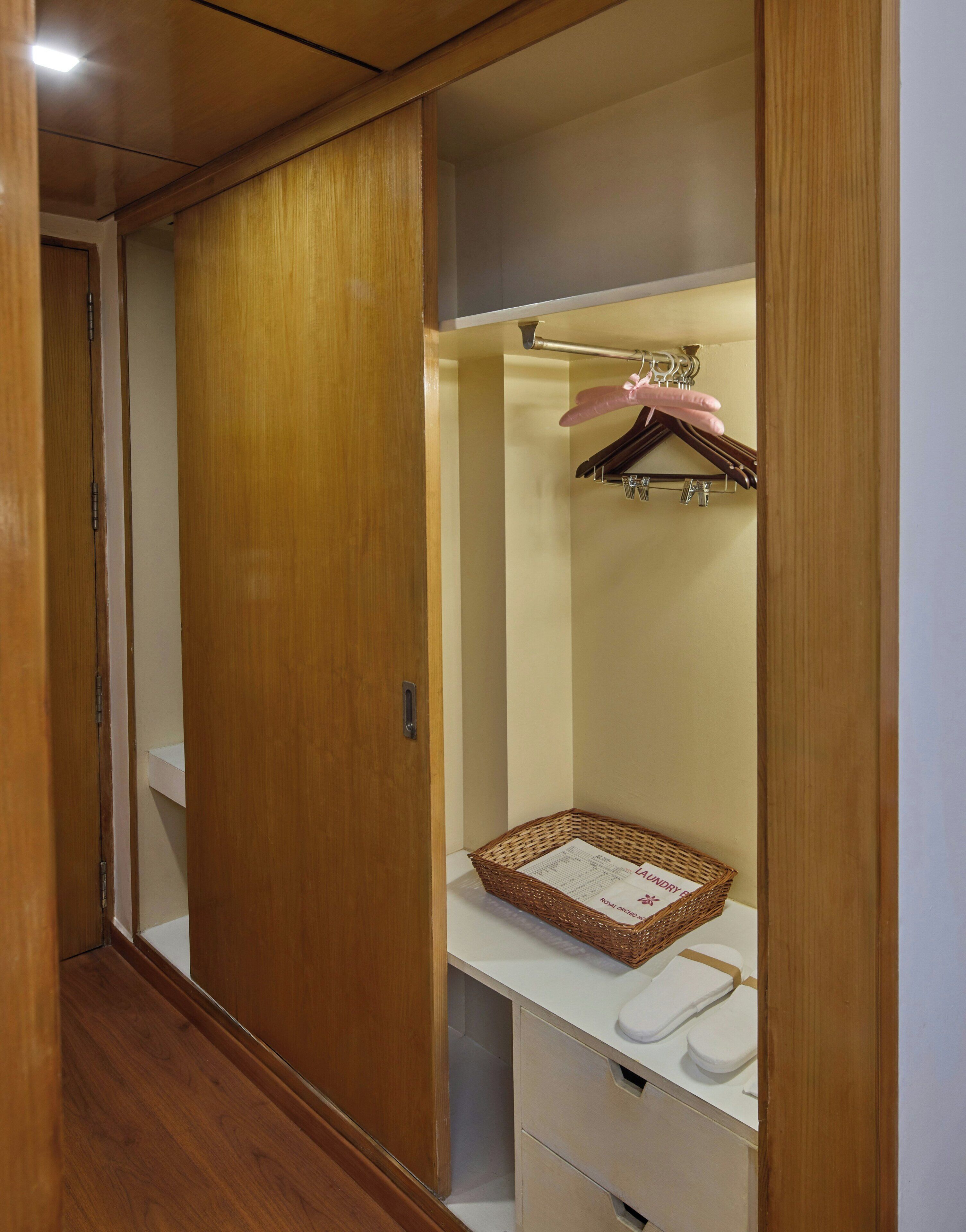 Un placard en bois avec une tringle pour suspendre les vêtements, un comptoir blanc et un panier muni d’une étiquette.