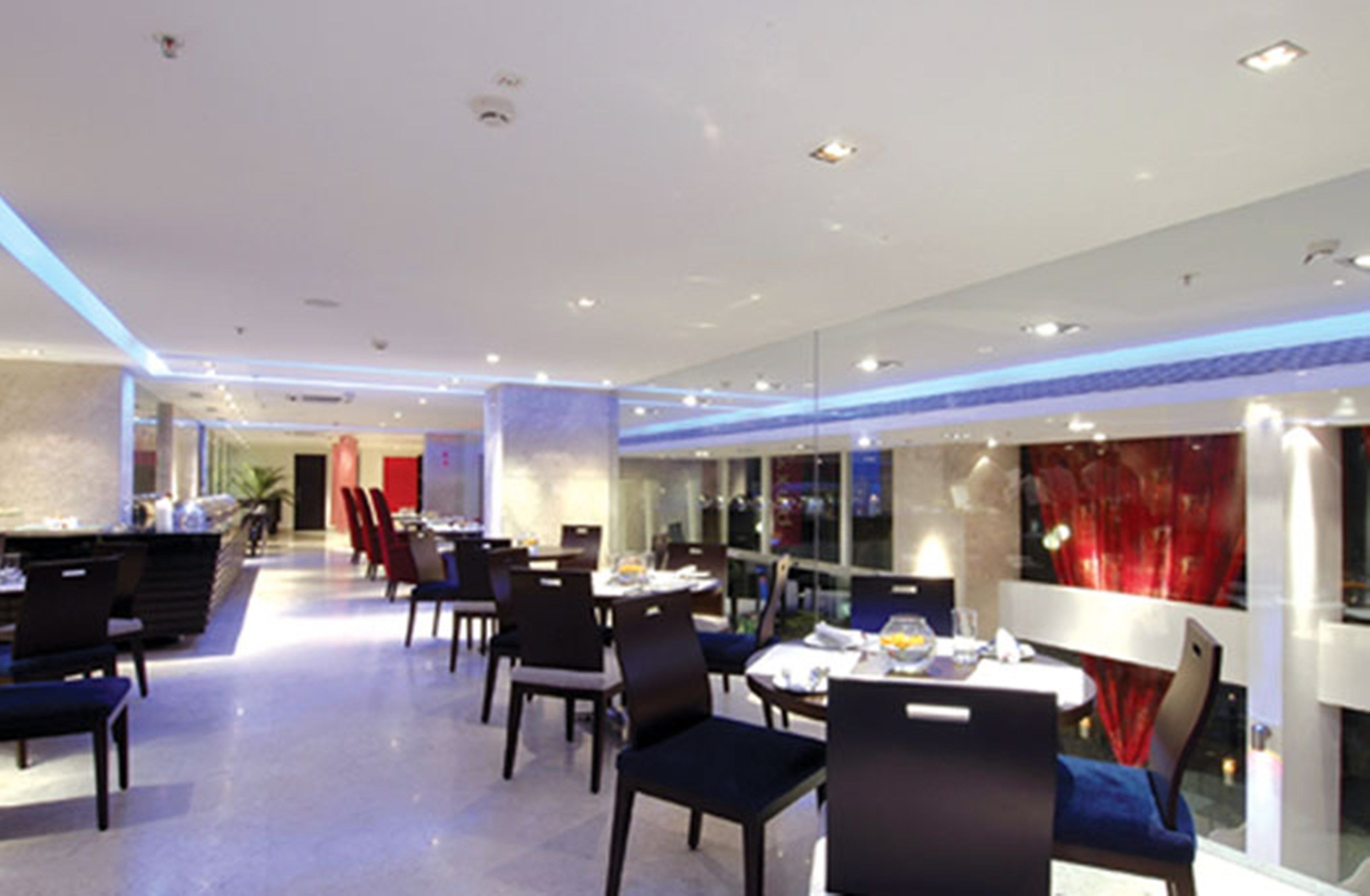 Un restaurante moderno con una barra larga, varias mesas y sillas.