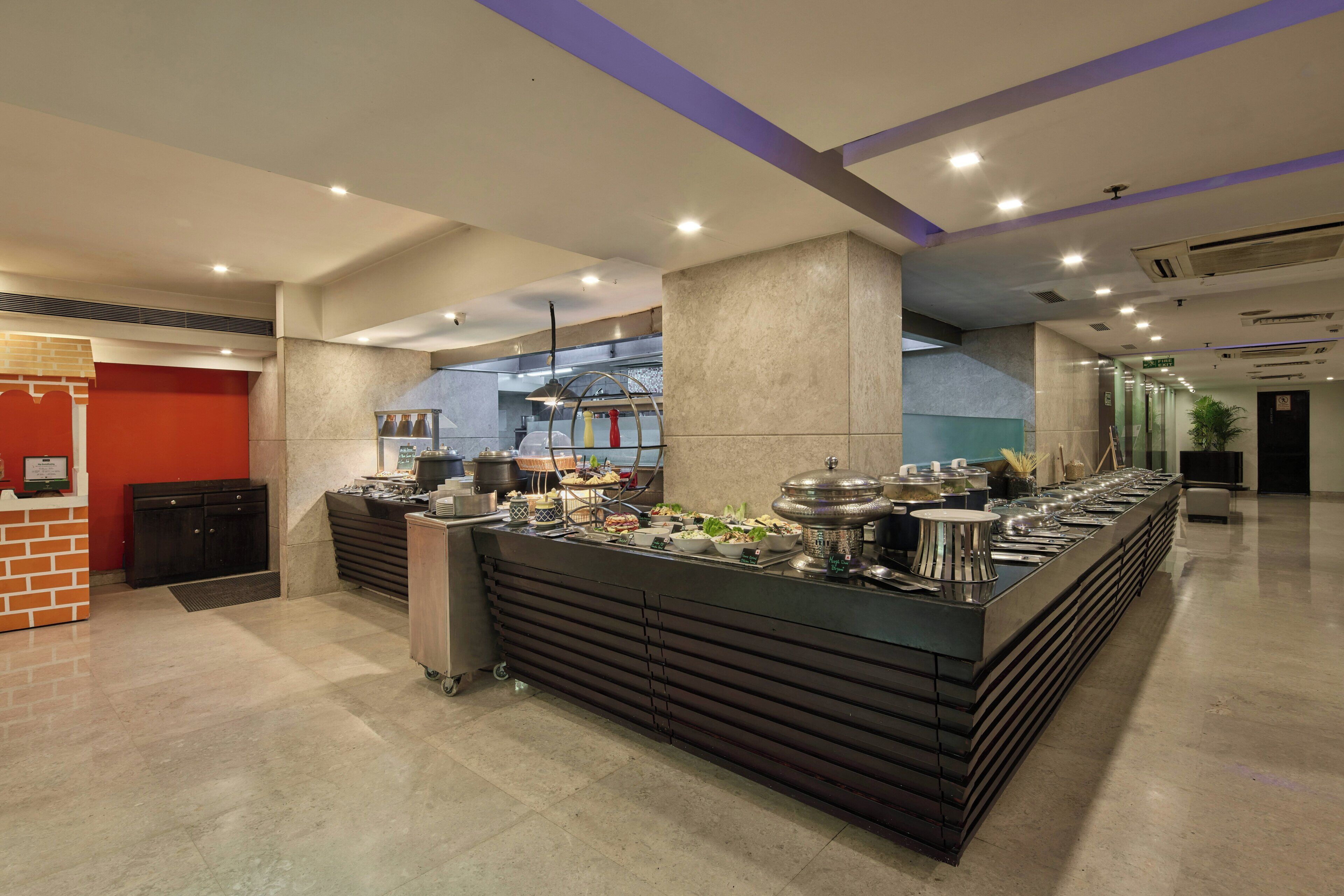 Un buffet disposé le long d’un long comptoir, avec un espace cuisine et un comptoir d’accueil.
