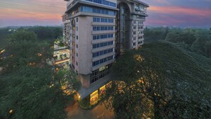 Een meerlaags hotel met een modern architectonisch ontwerp, met een opvallende hoekstructuur en een terras op het dak.