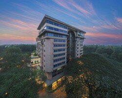 A multi-story hotel with a modern architectural design, featuring a prominent corner structure and a rooftop terrace.