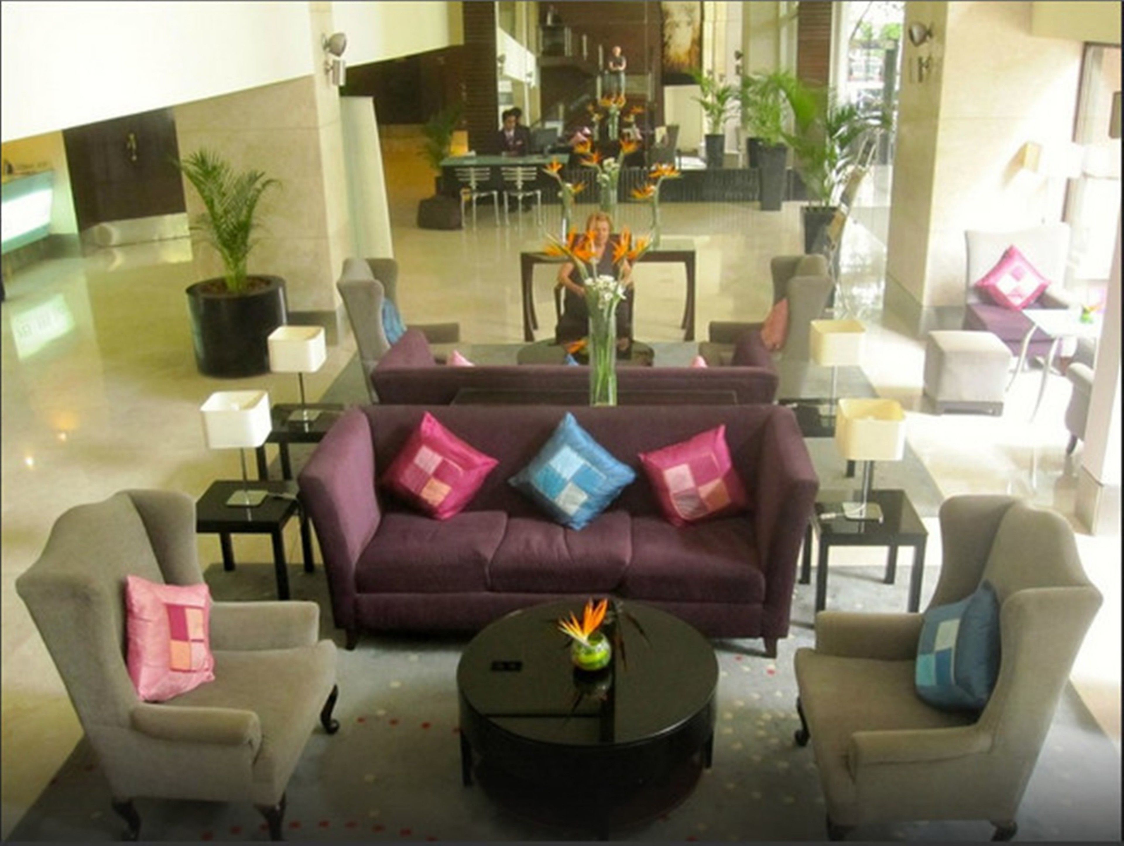 A lobby with a purple sofa, two armchairs, a coffee table, and a reception desk.