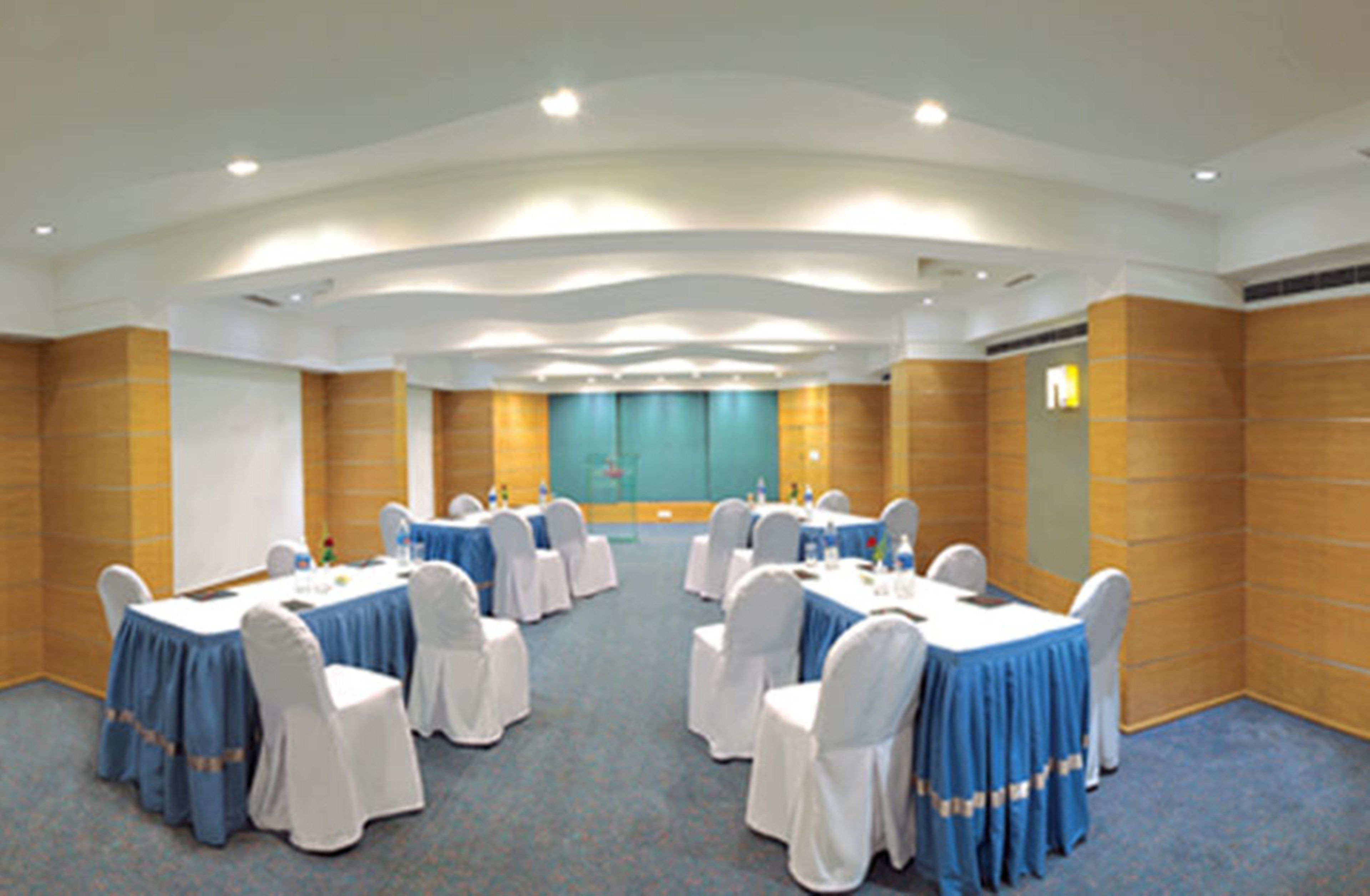 A conference room with round tables, white chairs, and blue tablecloths.
