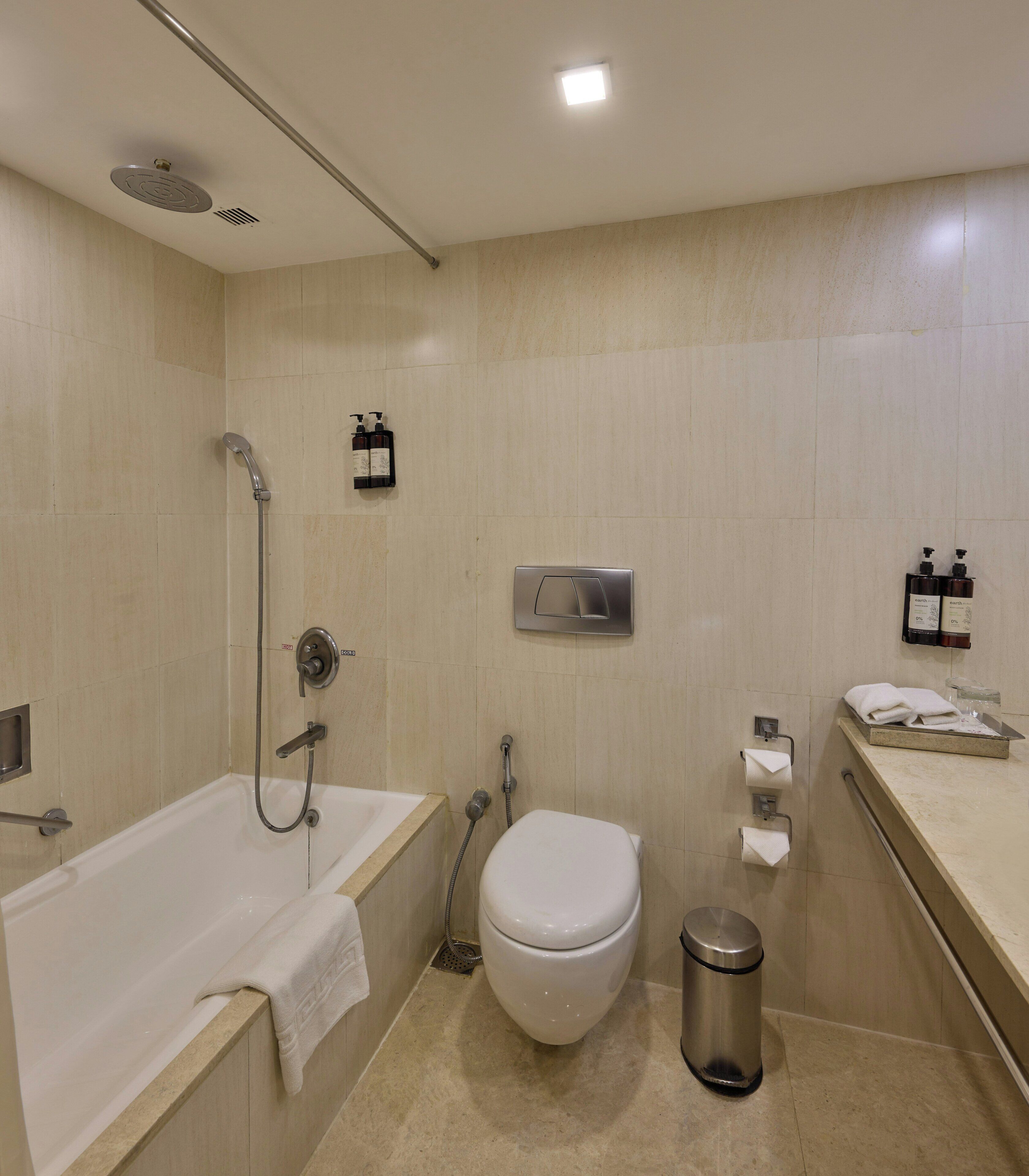 A modern bathroom with a bathtub, toilet, shower, and hand dryer.