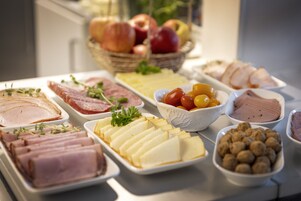 Un bufé con diversas opciones de comida, incluyendo carnes, quesos y frutas.