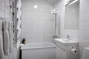 Un baño moderno con bañera, ducha, lavamanos e inodoro.