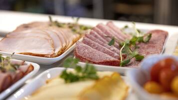 A variety of sliced meats and cheeses on a buffet table.