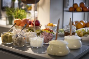 A buffet table with various food items and condiments. - Hotell Skövde (Skovde)