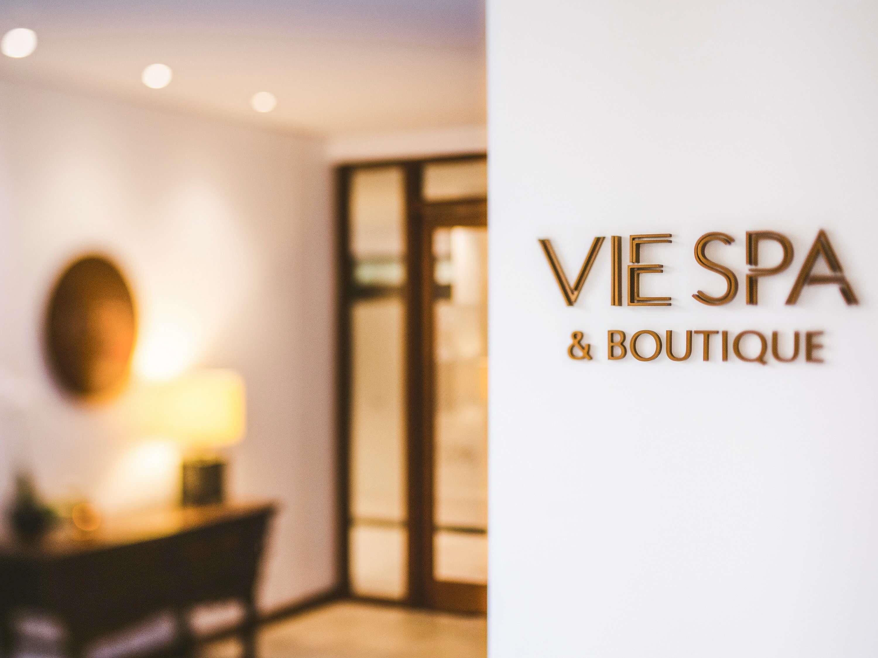 A blurred interior of a spa and boutique with a visible sign reading 'VIE SPA & BOUTIQUE.'