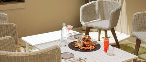 Une table à manger avec des fruits de mer, un cocktail et une bouteille d’eau.