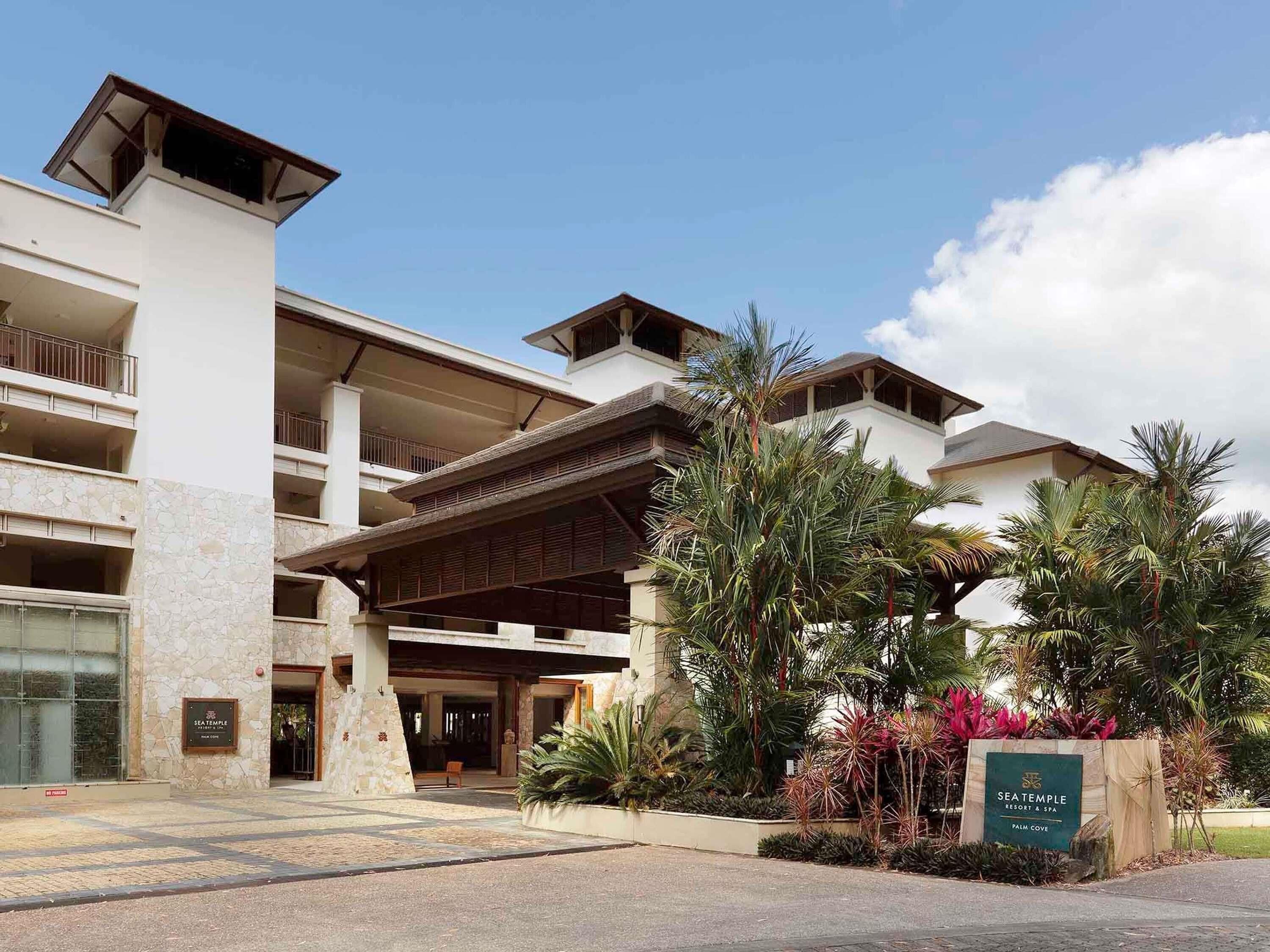 A multi-story hotel with a stone facade, balconies, and a covered entrance.