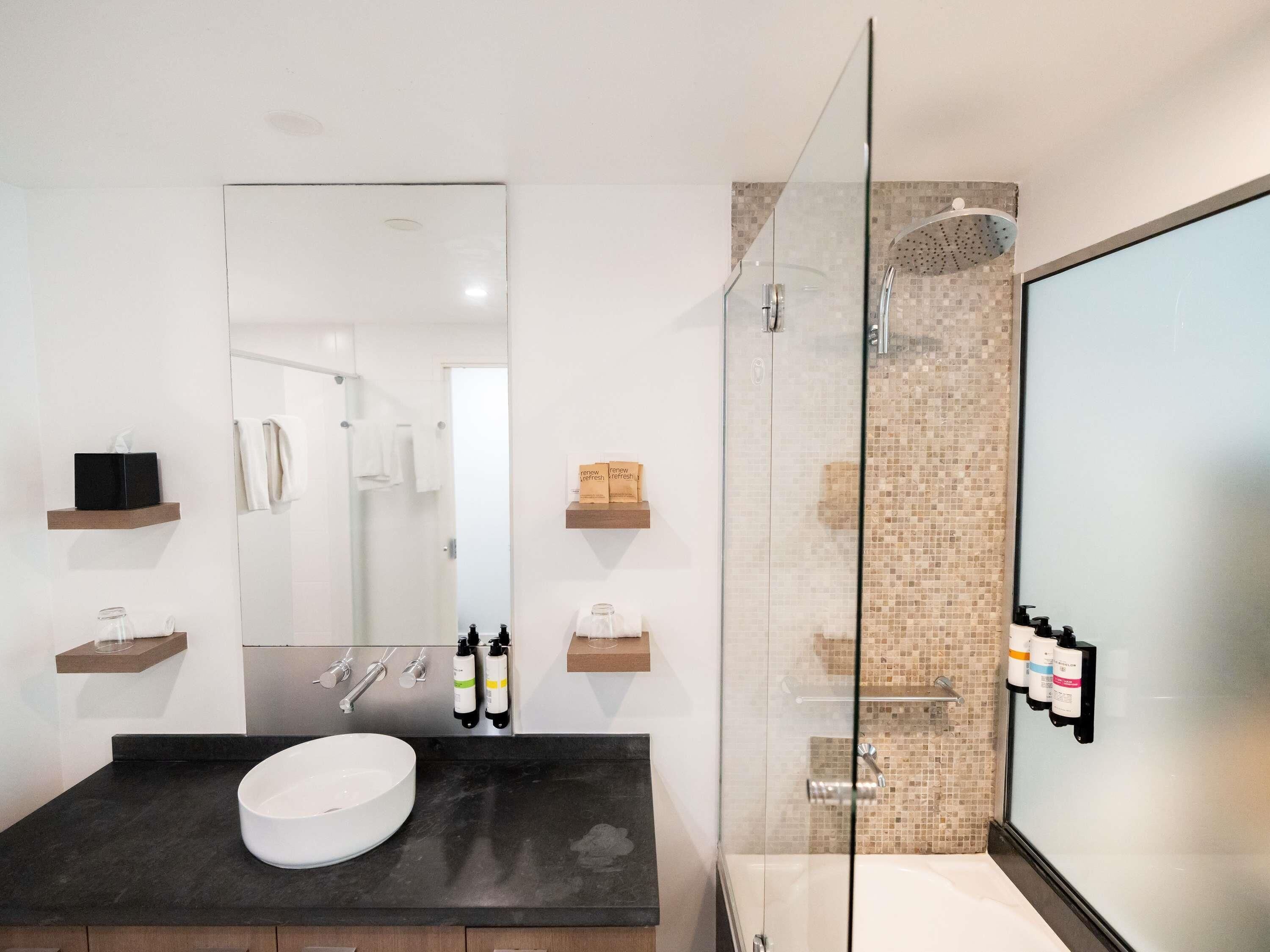 A modern bathroom with a glass-enclosed shower, a white sink, and a large mirror.