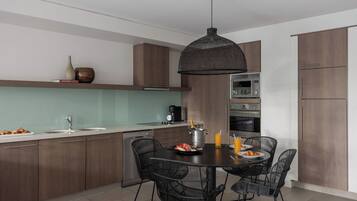 A modern kitchen with a dining area, featuring a central island, dark wooden cabinets, and a hanging light fixture.
