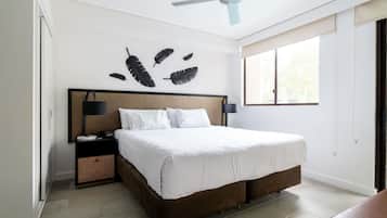 A bedroom with a bed, a ceiling fan, a nightstand, a lamp, and a window.