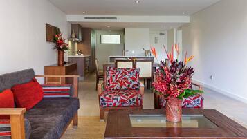 A modern living room with a sofa, chairs, a coffee table, and a kitchen area in the background.