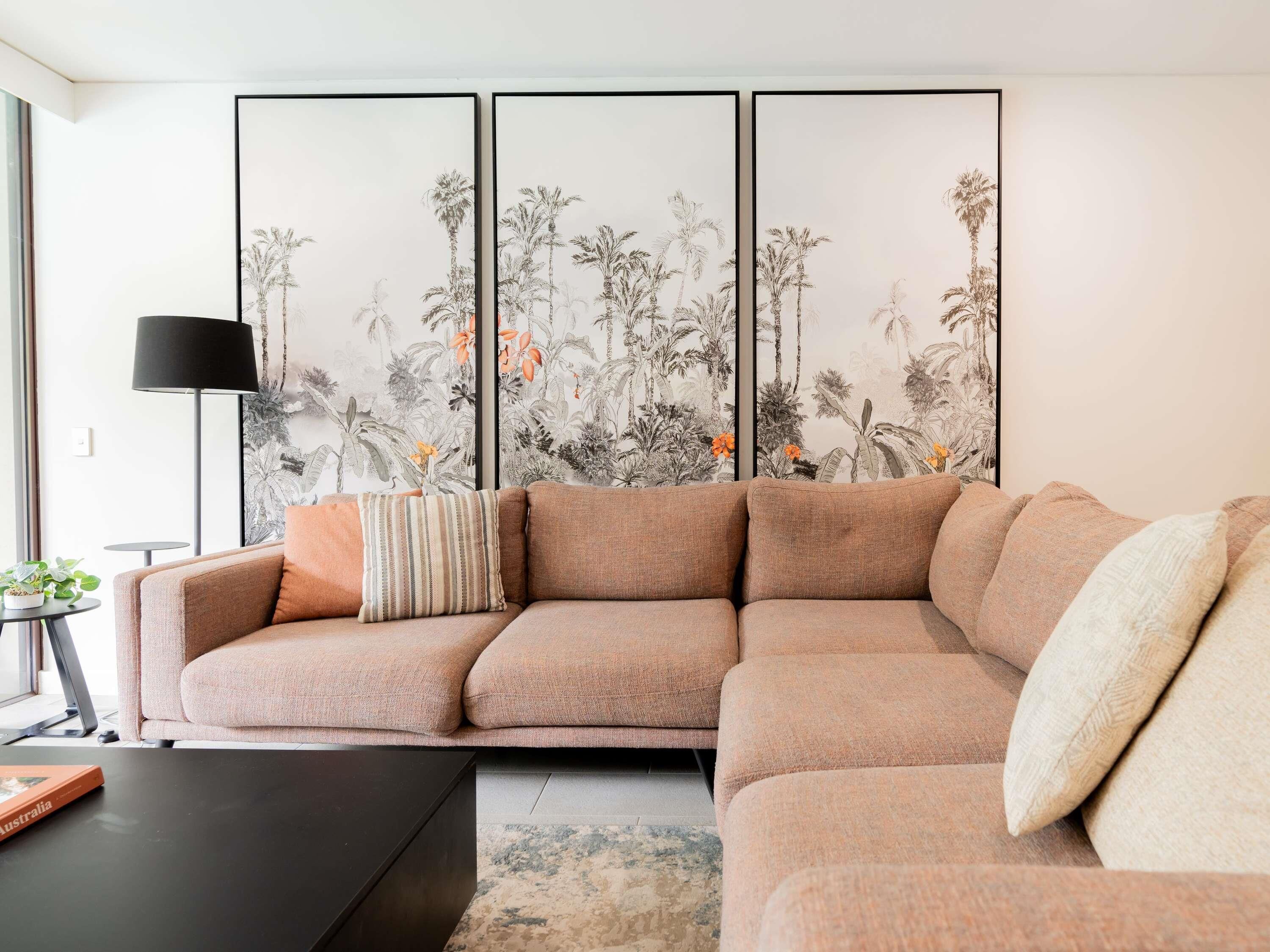 A modern living room with a sectional sofa, a black coffee table, and a large wall mural.