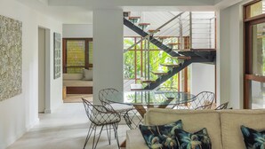 Ein modernes Interieur mit einer Treppe, einem Essbereich mit Stühlen und einer Couch mit Kissen.