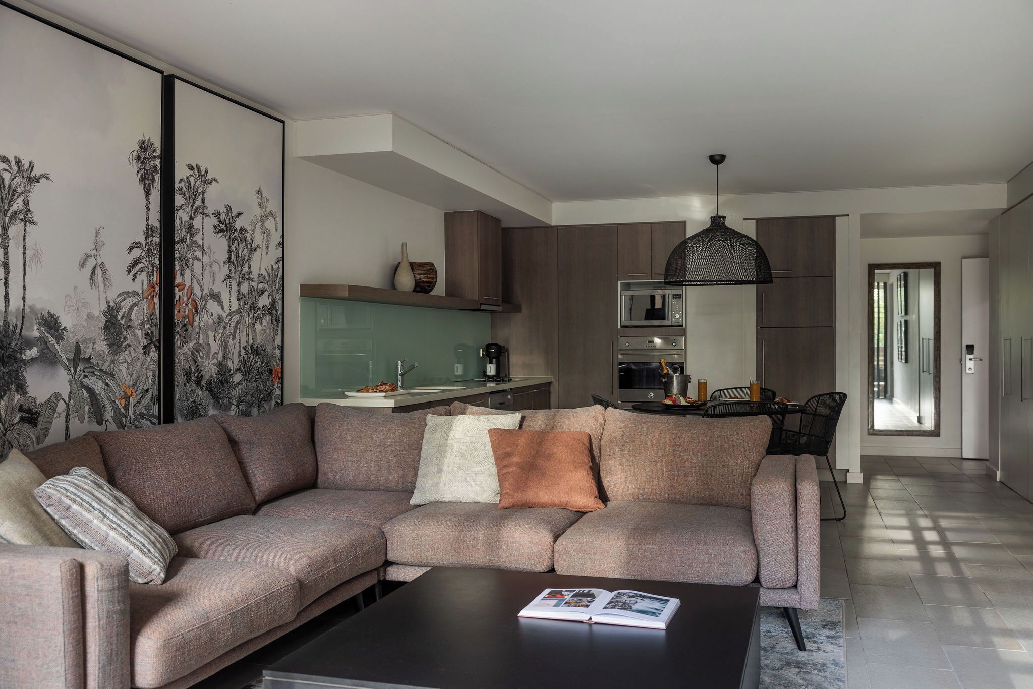 A modern living room with a sectional sofa, a coffee table, and a dining area with a table and chairs.