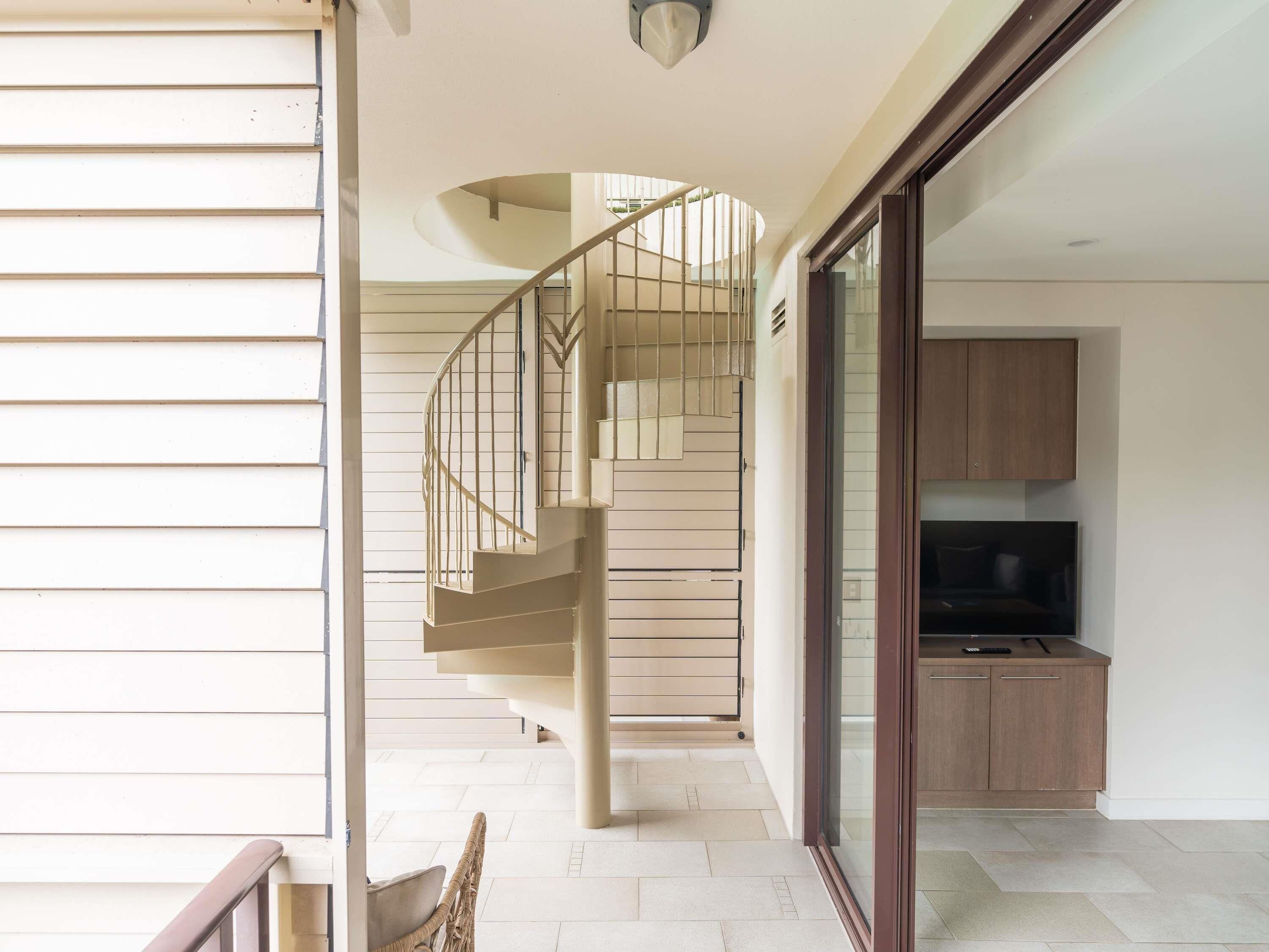 A modern interior with a spiral staircase, a dining area, and a kitchen.