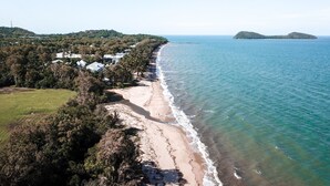 Eine Küstenlandschaft mit Strand, einem Steg und einer kleinen Insel in der Ferne.